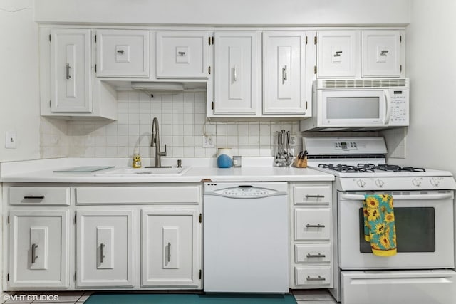 kitchen featuring light countertops, white appliances, a sink, and tasteful backsplash