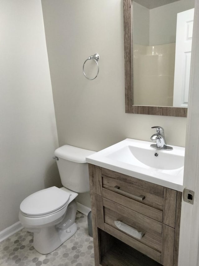 bathroom featuring toilet, baseboards, and vanity