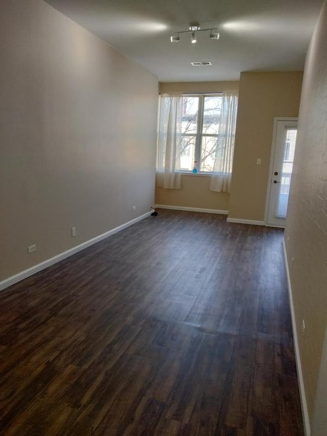 empty room featuring dark wood finished floors and baseboards