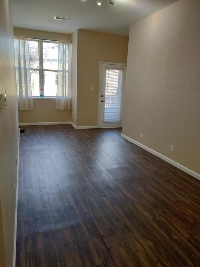 unfurnished room featuring dark wood-type flooring and a healthy amount of sunlight