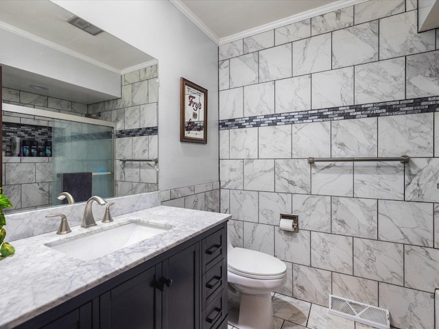 bathroom featuring a shower with door, tile walls, vanity, ornamental molding, and toilet