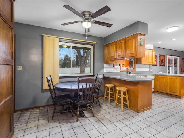 kitchen with sink, a breakfast bar area, kitchen peninsula, and light tile patterned flooring