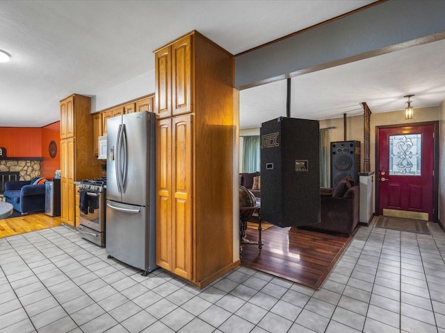 kitchen featuring stainless steel appliances, a stone fireplace, and light tile patterned floors