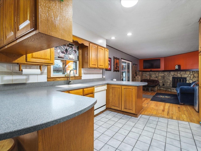 kitchen with sink, light tile patterned floors, white dishwasher, and kitchen peninsula