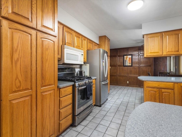 kitchen featuring light tile patterned floors, wooden walls, and stainless steel appliances