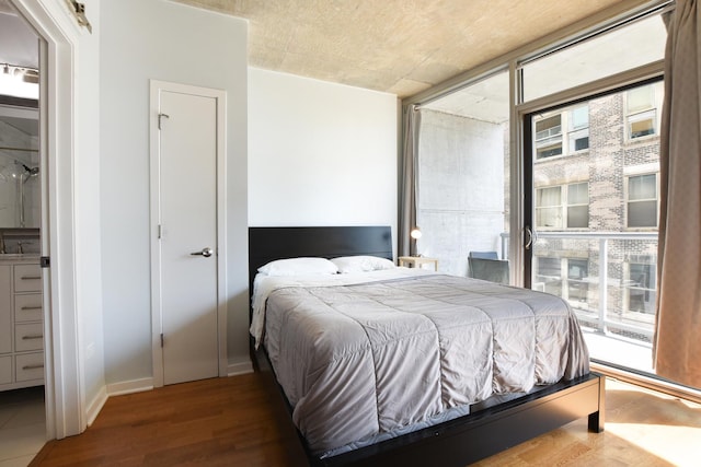 bedroom with wood-type flooring, floor to ceiling windows, and access to outside