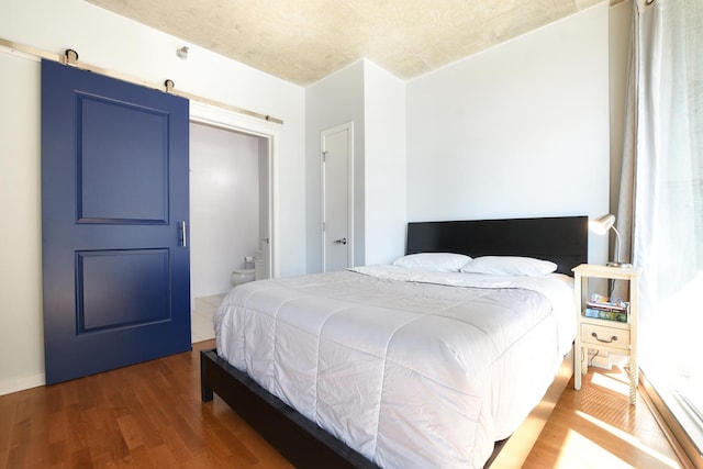 bedroom featuring a barn door and dark hardwood / wood-style floors