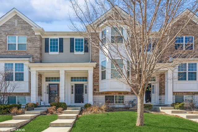 view of property with brick siding and a front lawn