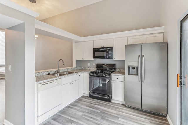 kitchen with sink, white cabinetry, black appliances, light stone countertops, and light wood-type flooring