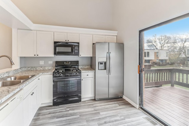 kitchen with white cabinetry, sink, black appliances, and light hardwood / wood-style floors