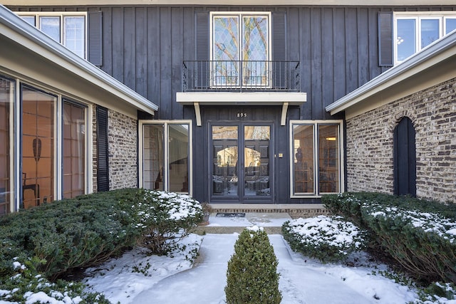 snow covered property entrance with a balcony