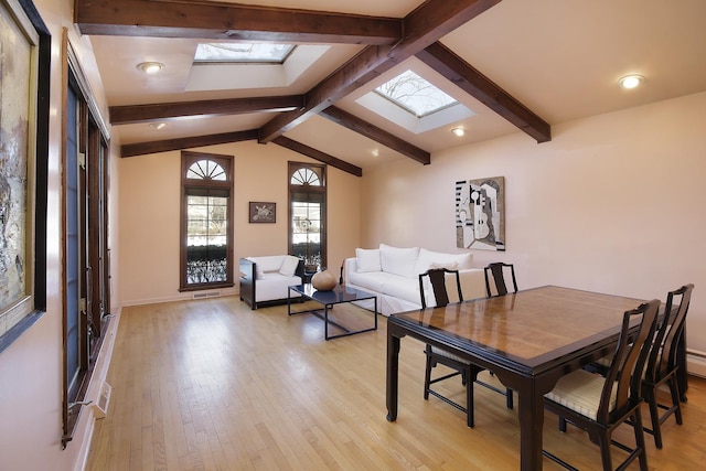 dining room with lofted ceiling with skylight and light wood-type flooring