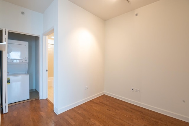 spare room featuring dark hardwood / wood-style floors and stacked washer / dryer