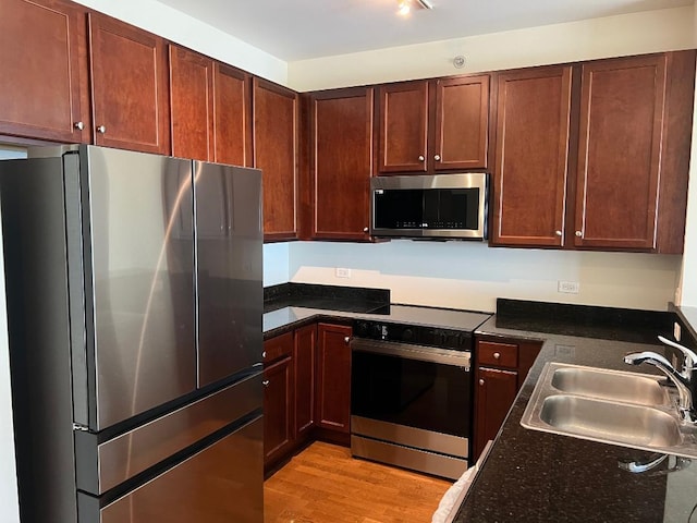 kitchen with appliances with stainless steel finishes, sink, and light hardwood / wood-style floors