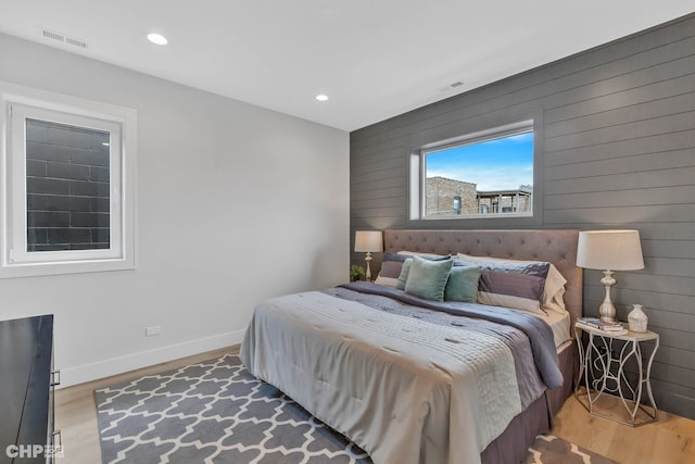 bedroom with wood-type flooring and wooden walls