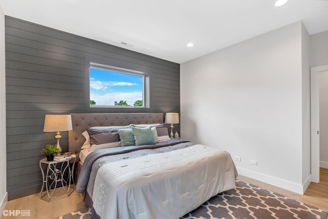 bedroom featuring wood-type flooring and wooden walls