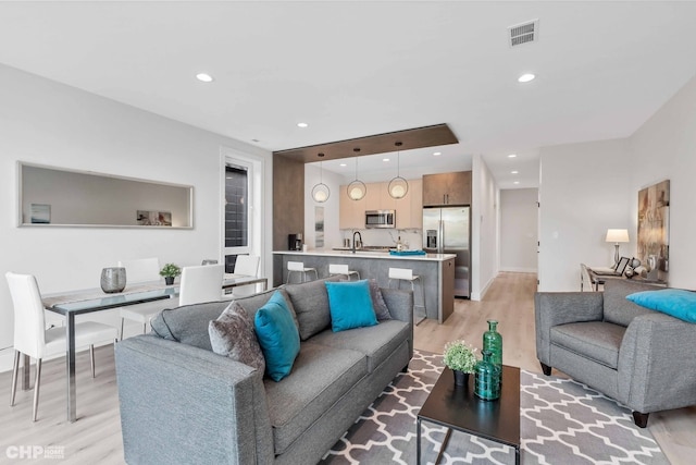 living room with sink and light hardwood / wood-style flooring