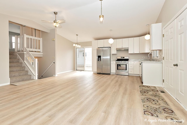 kitchen with sink, white cabinetry, hanging light fixtures, light wood-type flooring, and appliances with stainless steel finishes