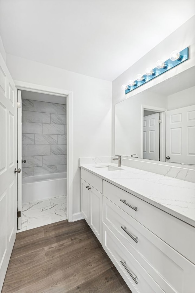 bathroom with vanity, hardwood / wood-style floors, and tiled shower / bath