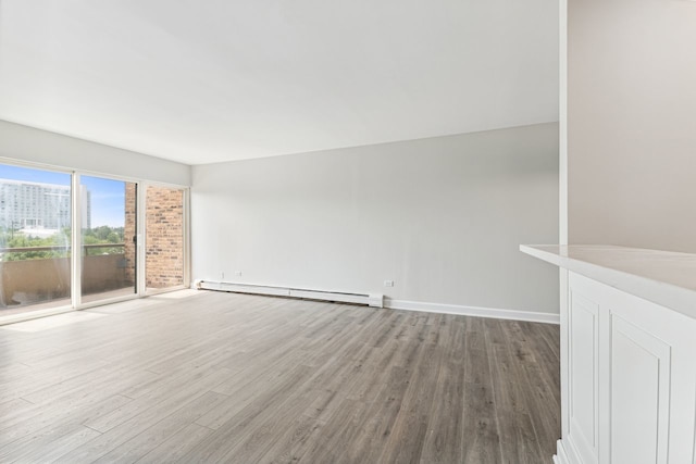 unfurnished room with baseboard heating and hardwood / wood-style floors