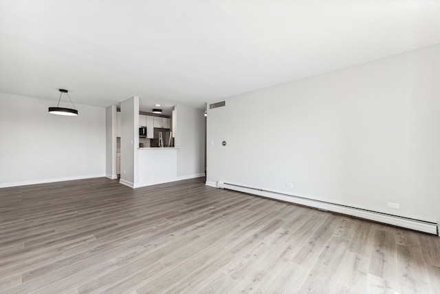 unfurnished living room featuring a baseboard heating unit and light wood-type flooring