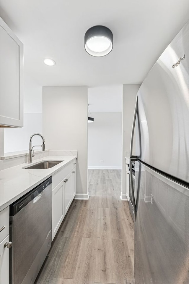 kitchen with white cabinetry, stainless steel appliances, light hardwood / wood-style floors, and sink