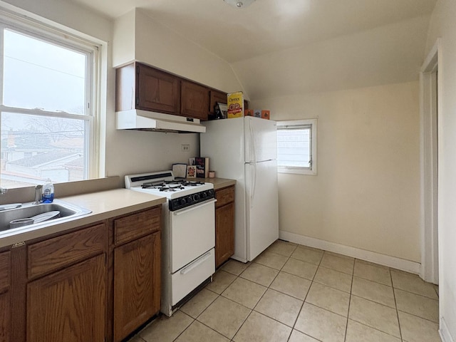 kitchen featuring white appliances, lofted ceiling, sink, and light tile patterned floors