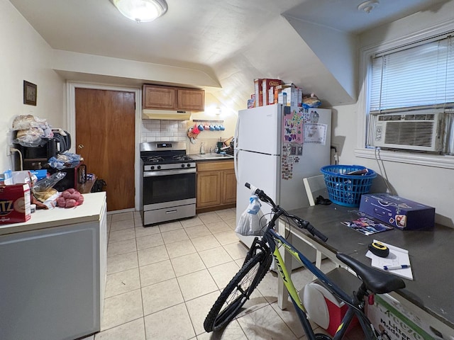 kitchen with white refrigerator, stainless steel gas range oven, light tile patterned floors, and backsplash