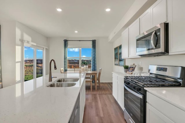 kitchen with sink, light hardwood / wood-style flooring, stainless steel appliances, light stone counters, and white cabinets