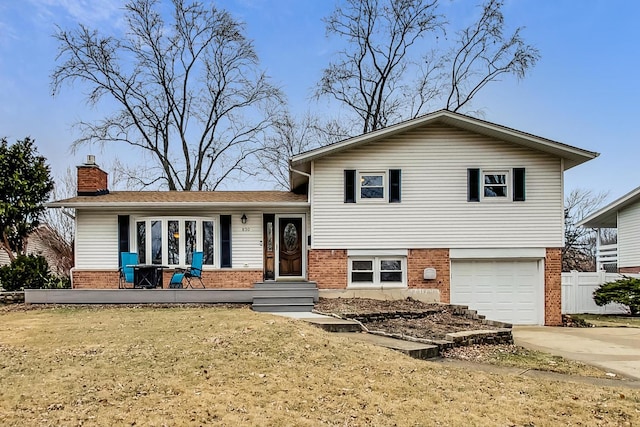 split level home with a garage, brick siding, fence, driveway, and a chimney