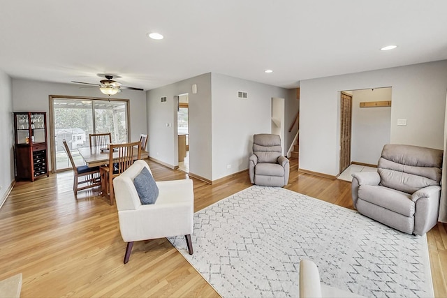 living room featuring recessed lighting, light wood-style flooring, baseboards, and stairs