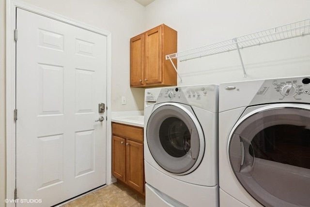 clothes washing area with cabinets, separate washer and dryer, and light tile patterned floors