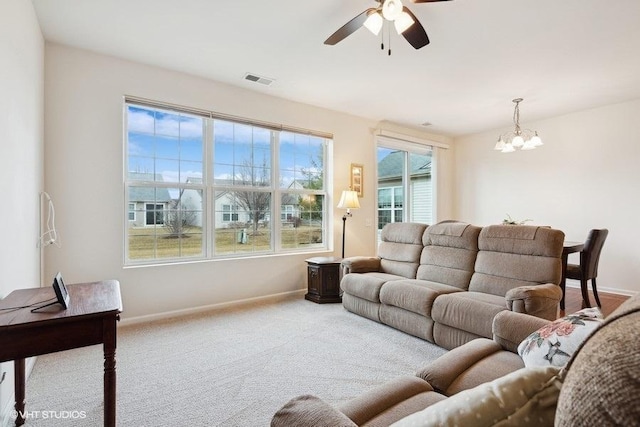 living room with ceiling fan with notable chandelier and carpet floors