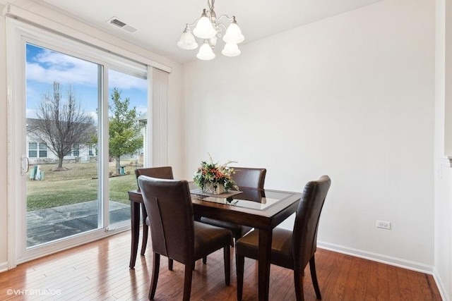 dining space featuring hardwood / wood-style floors, a wealth of natural light, and a chandelier