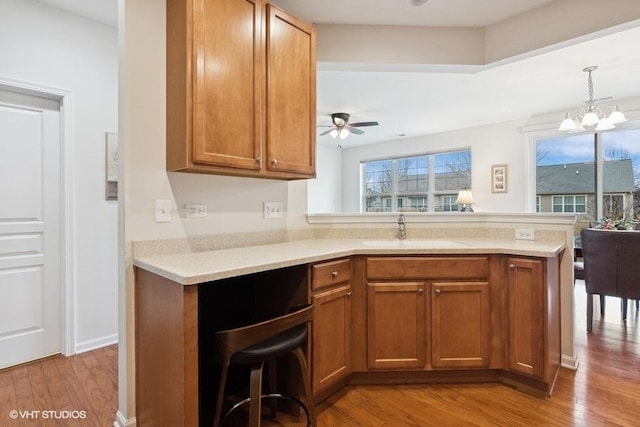 kitchen featuring sink, light hardwood / wood-style flooring, kitchen peninsula, and a healthy amount of sunlight