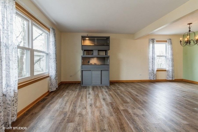 unfurnished living room with an inviting chandelier and hardwood / wood-style flooring