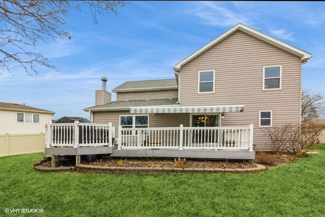 back of property featuring a wooden deck and a yard