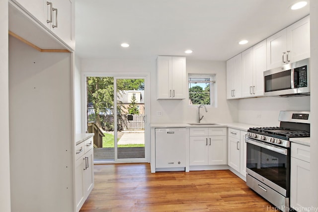 kitchen featuring appliances with stainless steel finishes, sink, white cabinets, and light hardwood / wood-style floors