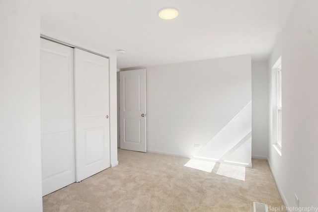 unfurnished bedroom featuring a closet and light carpet