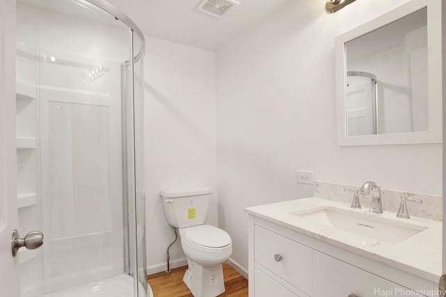 bathroom featuring vanity, hardwood / wood-style flooring, a shower with shower door, and toilet