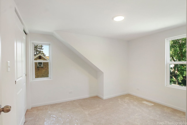 additional living space featuring vaulted ceiling and light carpet