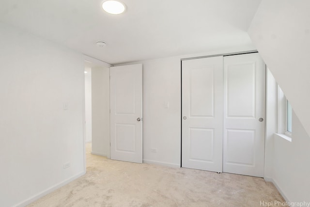 unfurnished bedroom with light carpet and a closet