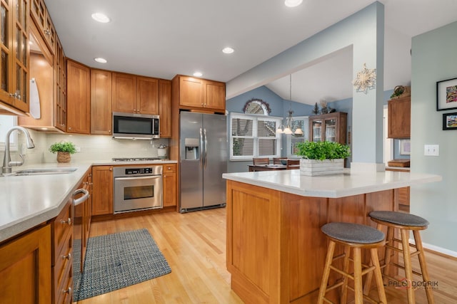 kitchen with a kitchen bar, sink, tasteful backsplash, hanging light fixtures, and stainless steel appliances