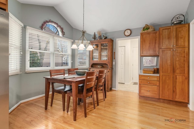 dining area with vaulted ceiling, light hardwood / wood-style floors, and a chandelier