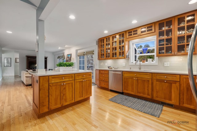 kitchen with stainless steel appliances, tasteful backsplash, sink, and light wood-type flooring