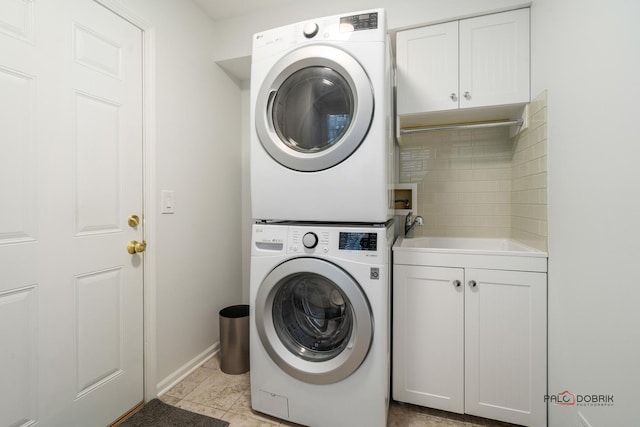 laundry area featuring cabinets, stacked washer / drying machine, and light tile patterned floors