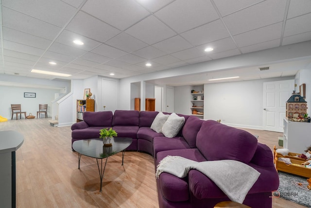 living room featuring a drop ceiling and light wood-type flooring