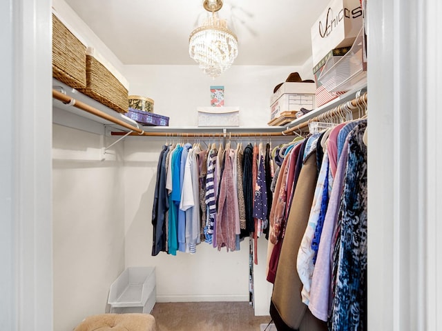 spacious closet with an inviting chandelier and carpet flooring