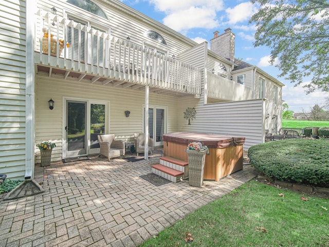 back of house with a hot tub, a patio, and a balcony