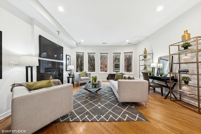 living room featuring a tiled fireplace and hardwood / wood-style flooring